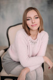 Soft photo of fresh young woman in pink tender sweater smiling. Pretty girl enjoying early sunny morning at home.