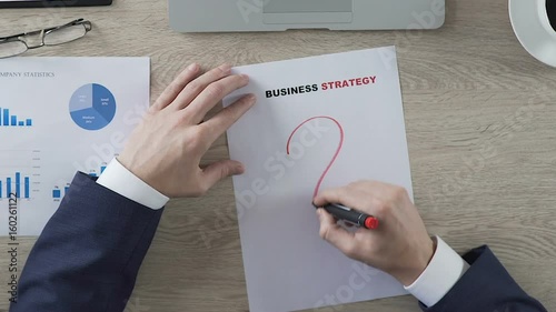 Male putting huge question mark in business strategy document, lack of ideas photo