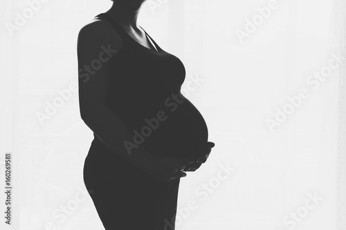 Pregnant woman standing against the window
