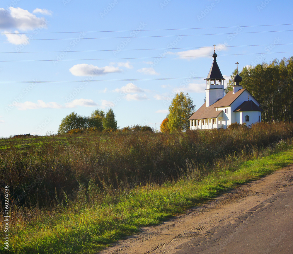 Standalone christian church on the green grassy hill under the sun. Moscow region, Russia.