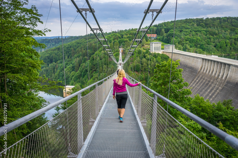 Obraz premium Girl walking over a suspension bridge