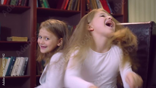 Two caucasian sisters different aged have fun laughing posing looking at the camera. Girlies dancing funny dance. photo