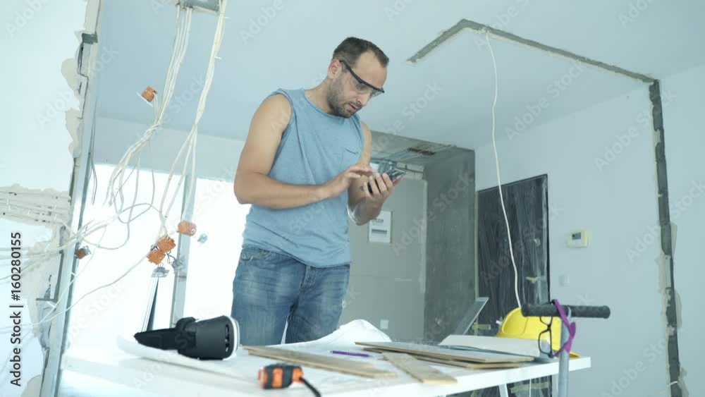 Young man with smartphone checking panels for new home
Young man with smartphone checking panels for new home