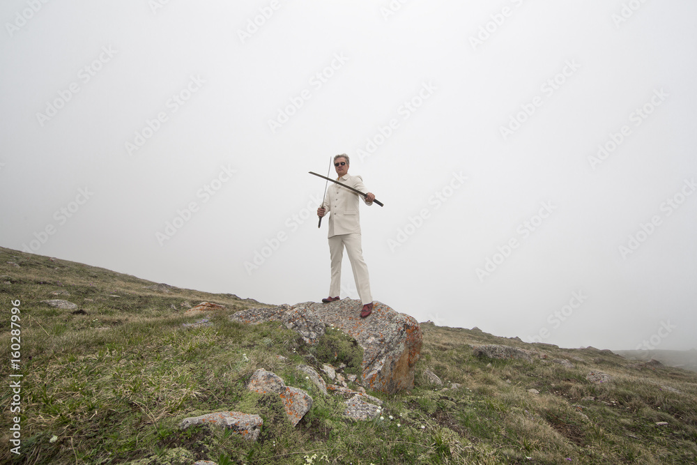 Obraz premium Businessman with swords in nature, man in mountains