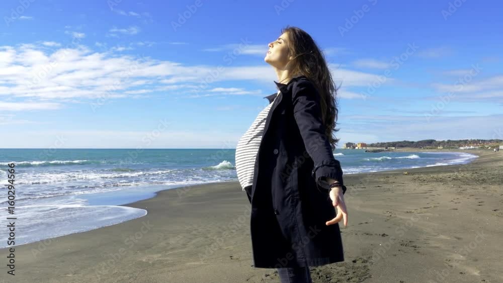 Happy pregnant woman enjoying the sun in front of the ocean Happy pregnant woman enjoying the sun in front of the ocean