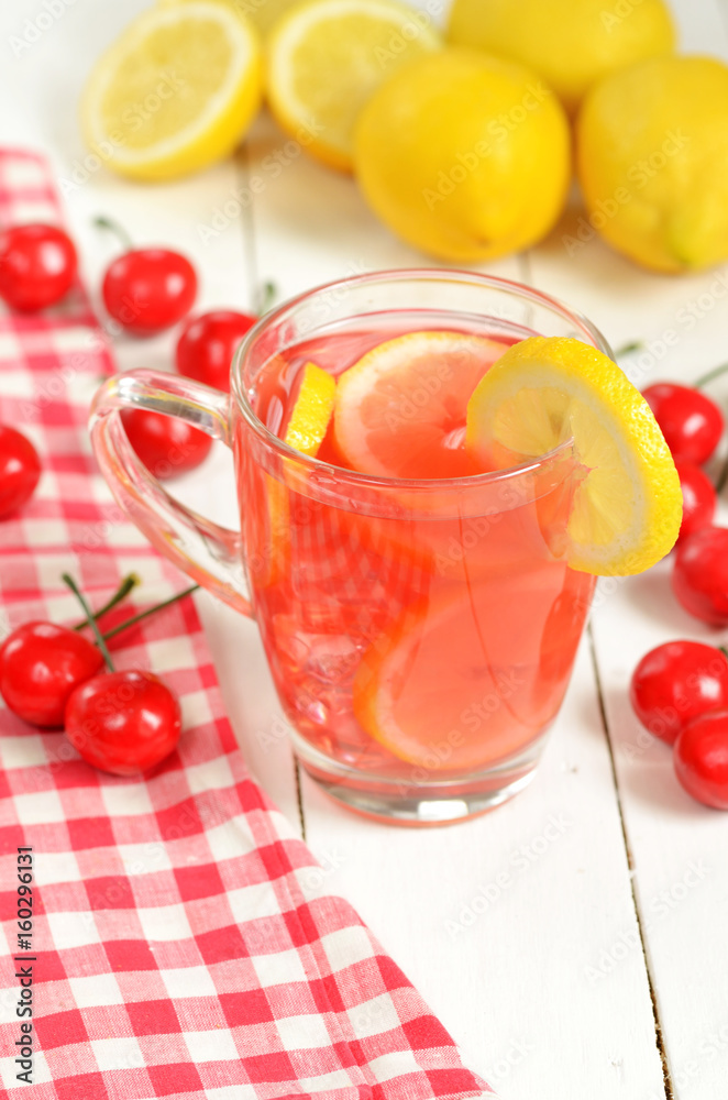 Fruit cherry tea with slice of lemon in mug and cherries Fruit cherry tea with slice of lemon in mug and cherries