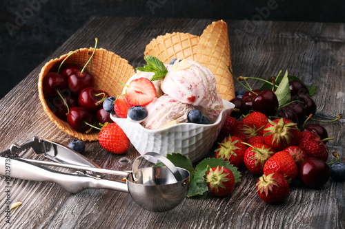 Strawberry ice cream in white bowl with fresh strawberries and blueberries photo