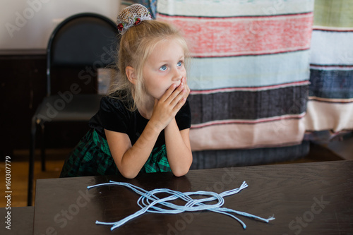 Obraz na plátně A nice little girl makes a sea knot from a cord in a workshop