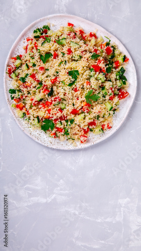 Tabbouleh salad with couscous on the plate.Traditional middle eastern or arab dish.Vegetarian.Parsley,pepper,cucumber,tomato,lemon.Middle eastern meze.Food or Healthy diet concept.Copy space for Text.