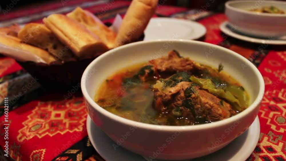 Delicious national Azerbaijani lamb soup in restaurant. Bouillon of meat in a white plate on a background of bread tortillas Delicious national Azerbaijani lamb soup in restaurant. Bouillon of meat in a white plate on a background of bread tortillas