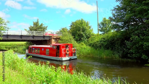 Colourful red barge sailing under bridge on canal photo