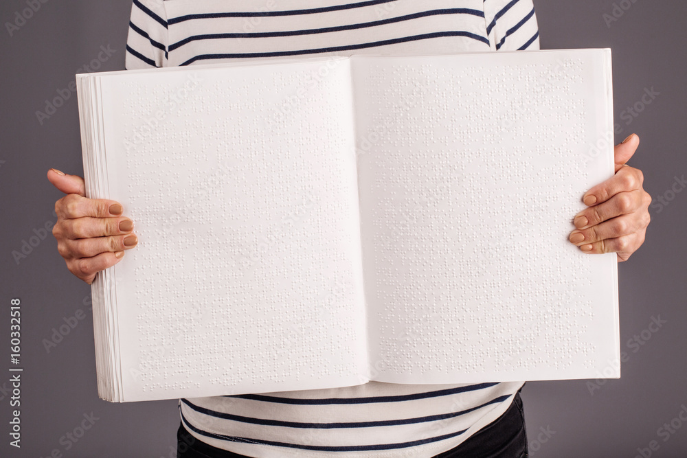 Obraz premium Hand holding a braille book. Woman show pages.