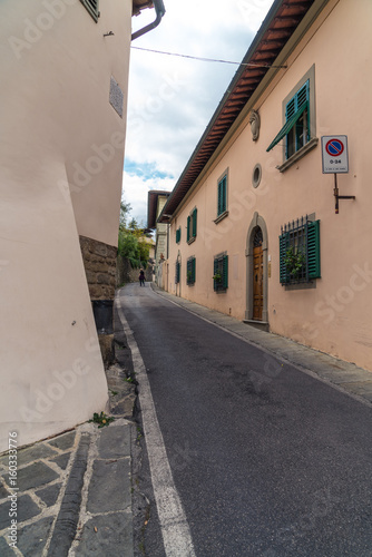 Narrow uphill street with walls on both sides in Fiesole, Italy