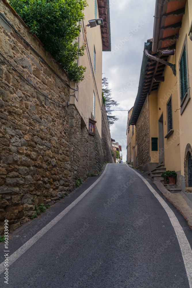 Narrow uphill street with walls on both sides in Fiesole, Italy