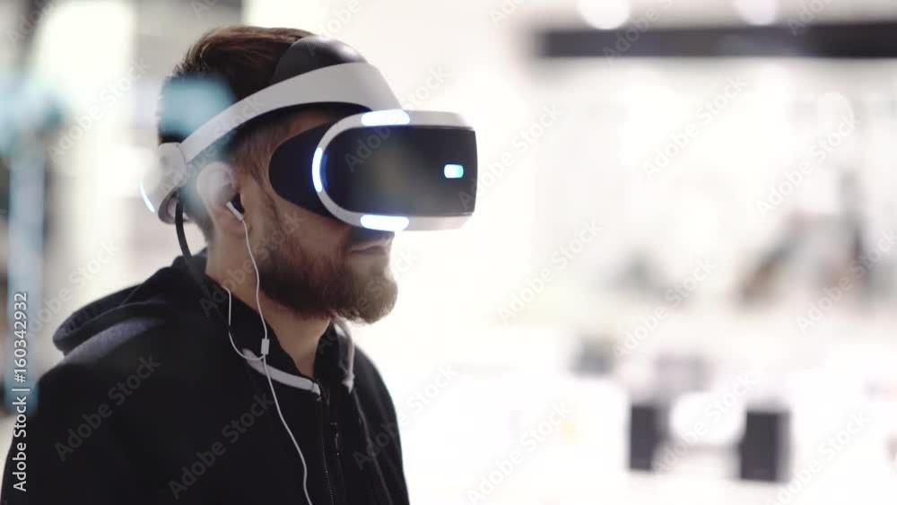 Bearded man uses VR-headset display with headphones for virtual reality game. UHD 4K Bearded man uses VR-headset display with headphones for virtual reality game. UHD 4K