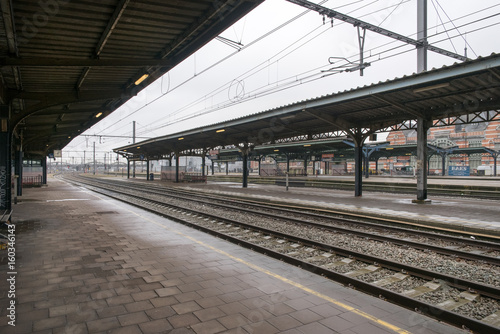 Railway station platform and train tracks with awning above, Belgium.
