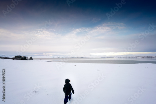 Child in distance walking in deep snow by day, Iceland, Europe.