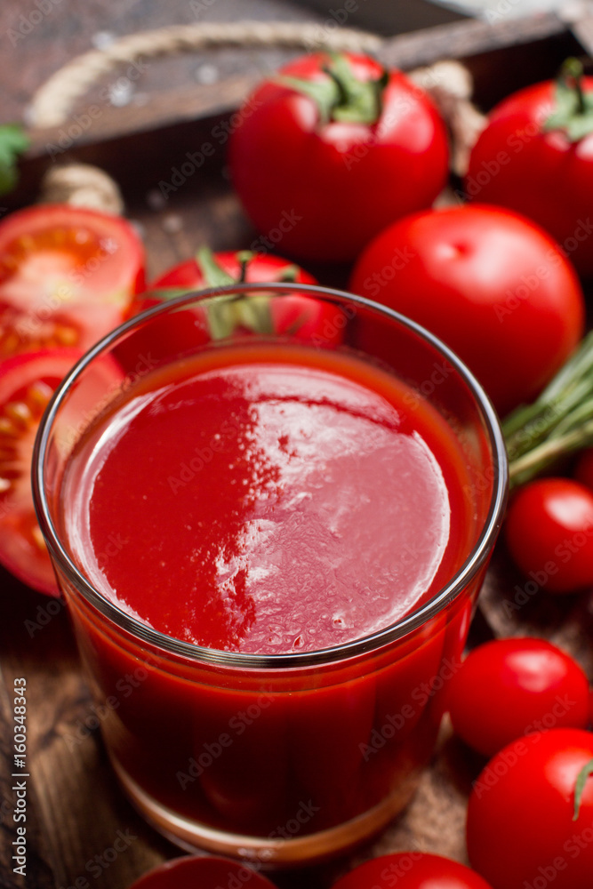 glass of tasty organic tomato juice and fresh tomatoes and herbs on wooden tray in rustic style. Selective focus, healthy lifestyle glass of tasty organic tomato juice and fresh tomatoes and herbs on wooden tray in rustic style. Selective focus, healthy lifestyle