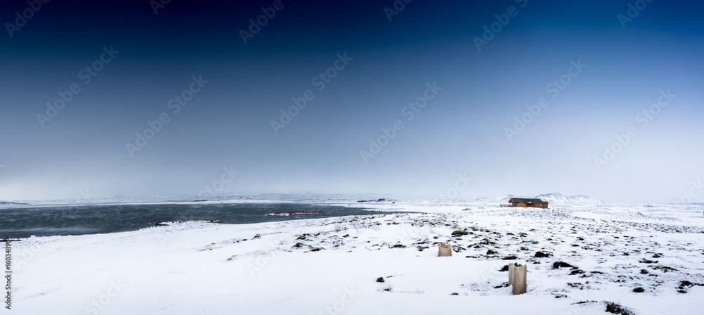 Log cabin in snow covered landscape, in distance, Iceland, Europe.