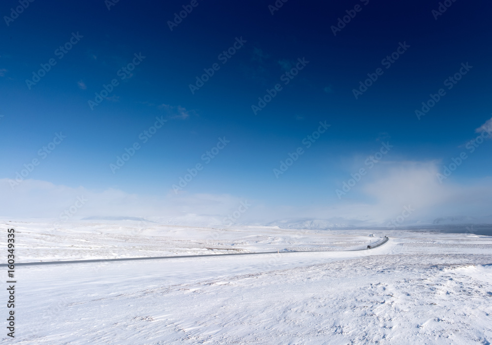 Snow covered landscape, distant mountain and blue sky, Iceland, Europe.