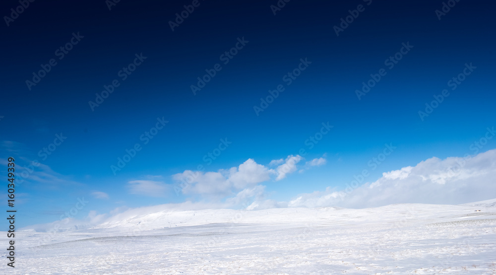 Snow covered landscape, distant mountain and blue sky, Iceland, Europe.