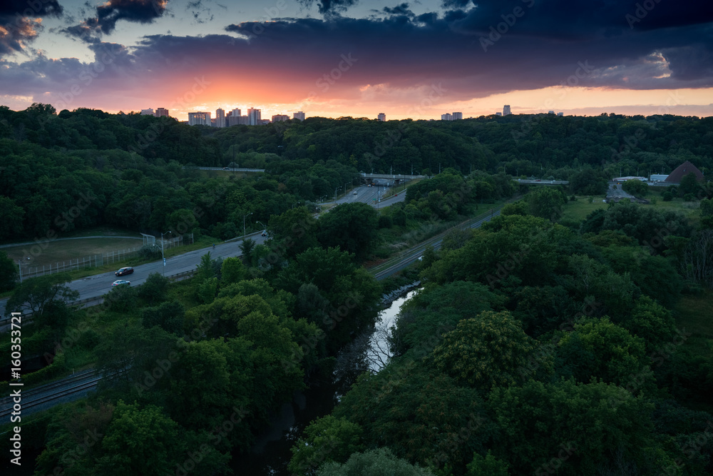 Skyline at sunset in background, roads through trees in foreground, Ontario, Canada.