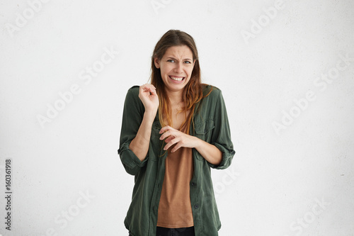 Brunette woman in casual clothes expressing disgust, unwillingness, dislike, disregard having tensive look frowning face. Cauasian woman with pleasant appearance looking indignant digusting something photo