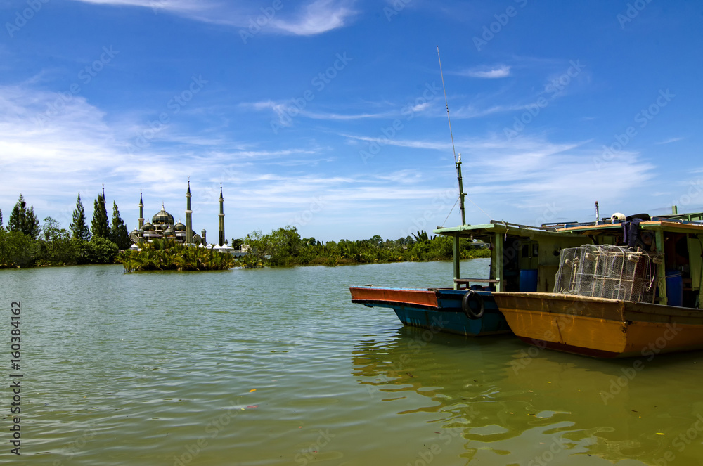 boat anchored near the river bank over crystal mosque and blue sky background at sunny day at Terengganu, Malaysia