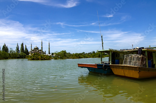 boat anchored near the river bank over crystal mosque and blue sky background at sunny day at Terengganu  Malaysia