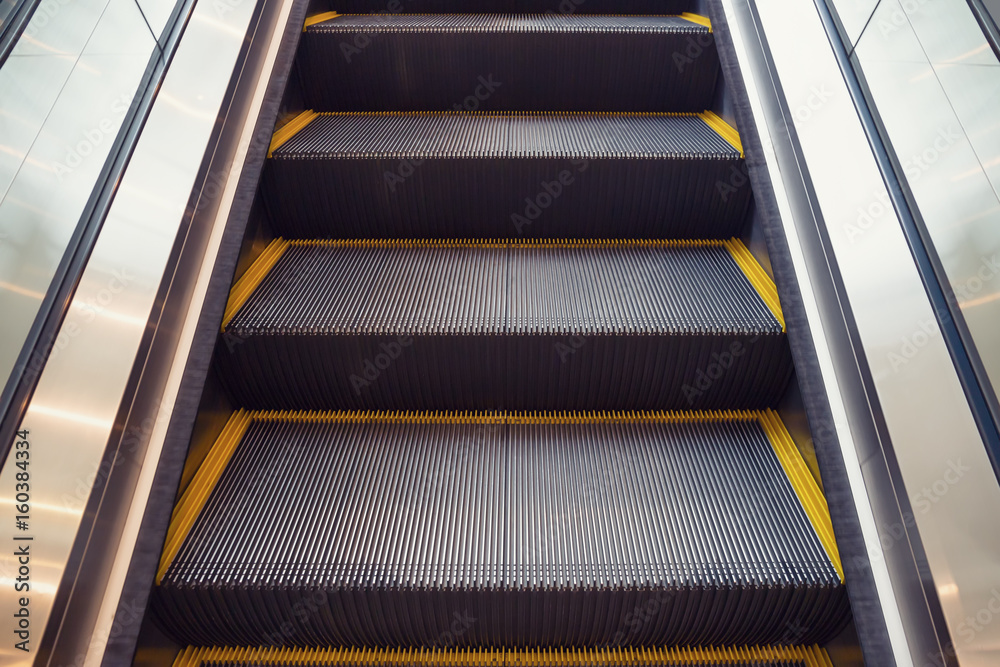 Empty escalator or moving stair. Also called stairway or staircase. Modern architecture design with step, glass for lift people up floor building i.e. shopping mall, airport, metro and subway station.
