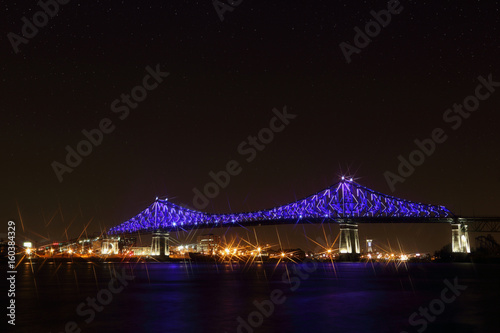 Jacques Cartier Bridge Illumination in Montreal, reflection in water. Montreal’s 375th anniversary. luminous colorful interactive Jacques Cartier Bridge. Bridge panoramic colorful silhouette by night.