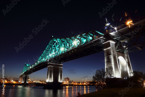 Jacques Cartier Bridge Illumination in Montreal, reflection in water. Montreal’s 375th anniversary. luminous colorful interactive Jacques Cartier Bridge. Bridge panoramic colorful silhouette by night.