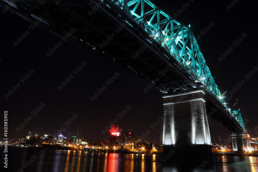 Jacques Cartier Bridge Illumination in Montreal, reflection in water. Montreal’s 375th anniversary. luminous colorful interactive Jacques Cartier Bridge. Bridge panoramic colorful silhouette by night.