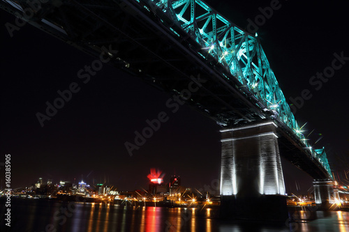 Jacques Cartier Bridge Illumination in Montreal  reflection in water. Montreal   s 375th anniversary. luminous colorful interactive Jacques Cartier Bridge. Bridge panoramic colorful silhouette by night.