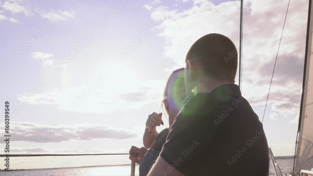 The girl with the young man sit on the white yacht having lowered legs from edge of the yacht. The young couple looks at a decline The girl with the young man sit on the white yacht having lowered legs from edge of the yacht. The young couple looks at a decline