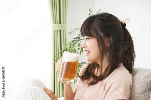 Young woman drinking beer at home