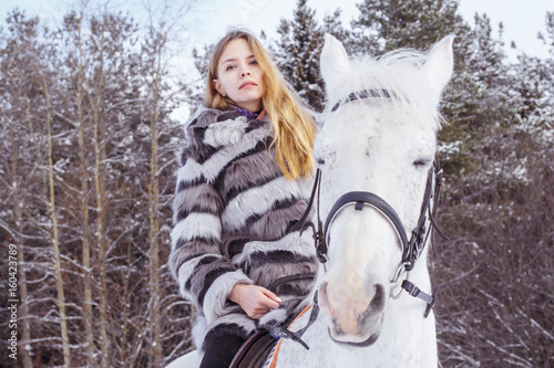 Nice girl and white horse in a forest in a winter