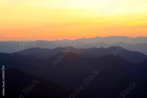 Beautiful Mountain And Sunset at doi come fah, chiang mai Thailand. Dark Silhouette of Mountains with Yellow Sunrise Background. © Nischaporn