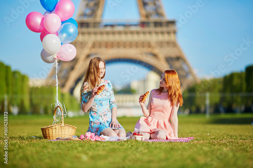 Two young women having picnic near the Eiffel tower in Paris, France photo