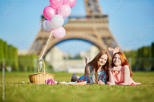 Two young women having picnic near the Eiffel tower in Paris, France photo