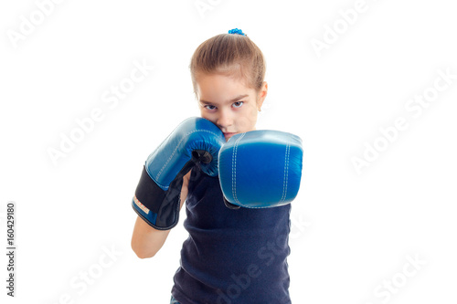 little serious girl with boxing gloves stands in front of the camera and pulls the hands