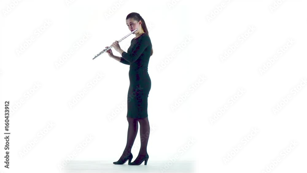 Woman plays on flute melody in slow motion. White studio Woman plays on flute melody in slow motion. White studio