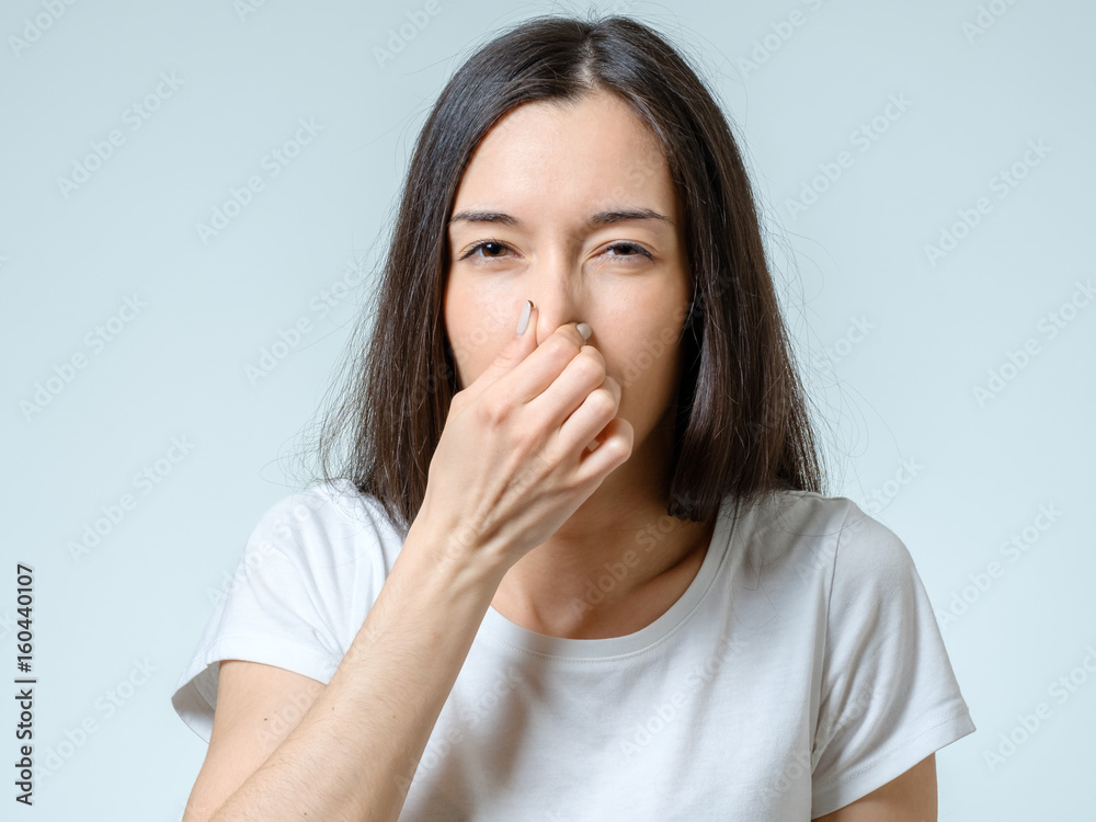 Girl covers nose with hand showing that something stinks Girl covers nose with hand showing that something stinks