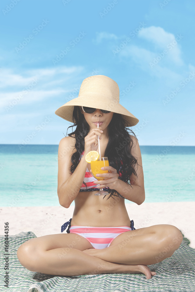 Woman drinks orange juice at seaside
