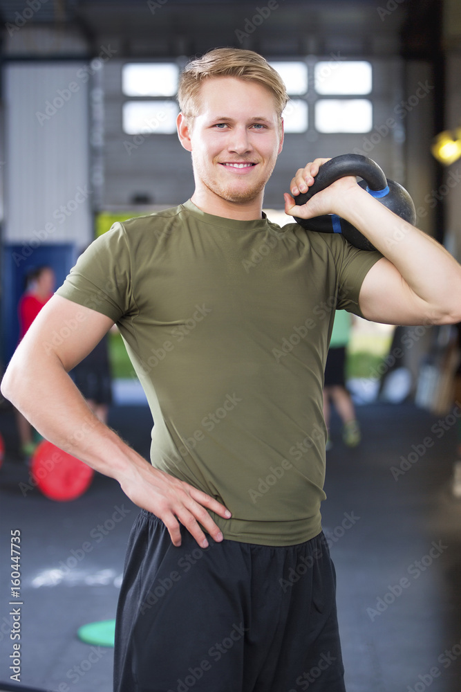 Confident Fit Male Athlete Holding Kettlebell In Health Club