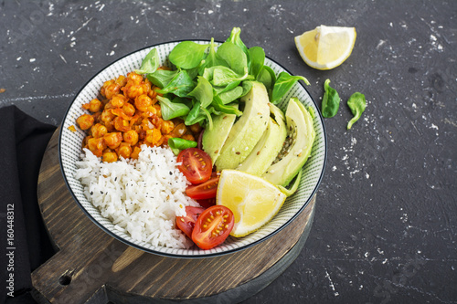 Healthy lunch bowl: basmati rice, chickpeas in tomato sauce, avocado, cherry tomatoes, corn salad. Top view