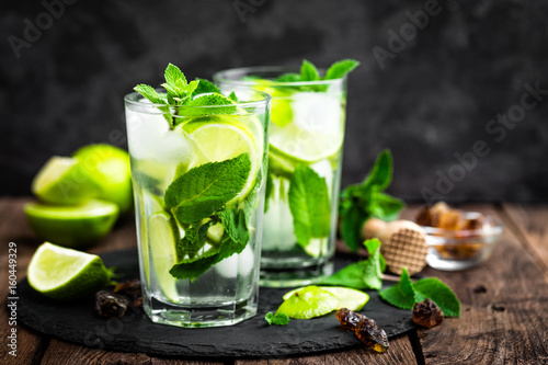 Refreshing mint cocktail mojito with rum and lime, cold drink or beverage with ice on black background photo