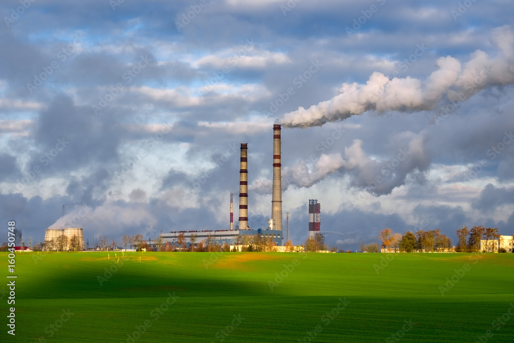 Emissions from industrial enterprises on the background of blue sky and green grass