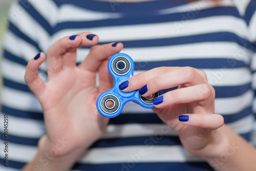 A girl is holding a popular toy fidget spinner in her hands. Stress relief. Anti stress and relaxation fidgets, spinner for tired people. Girl playing with a fidget spinner.