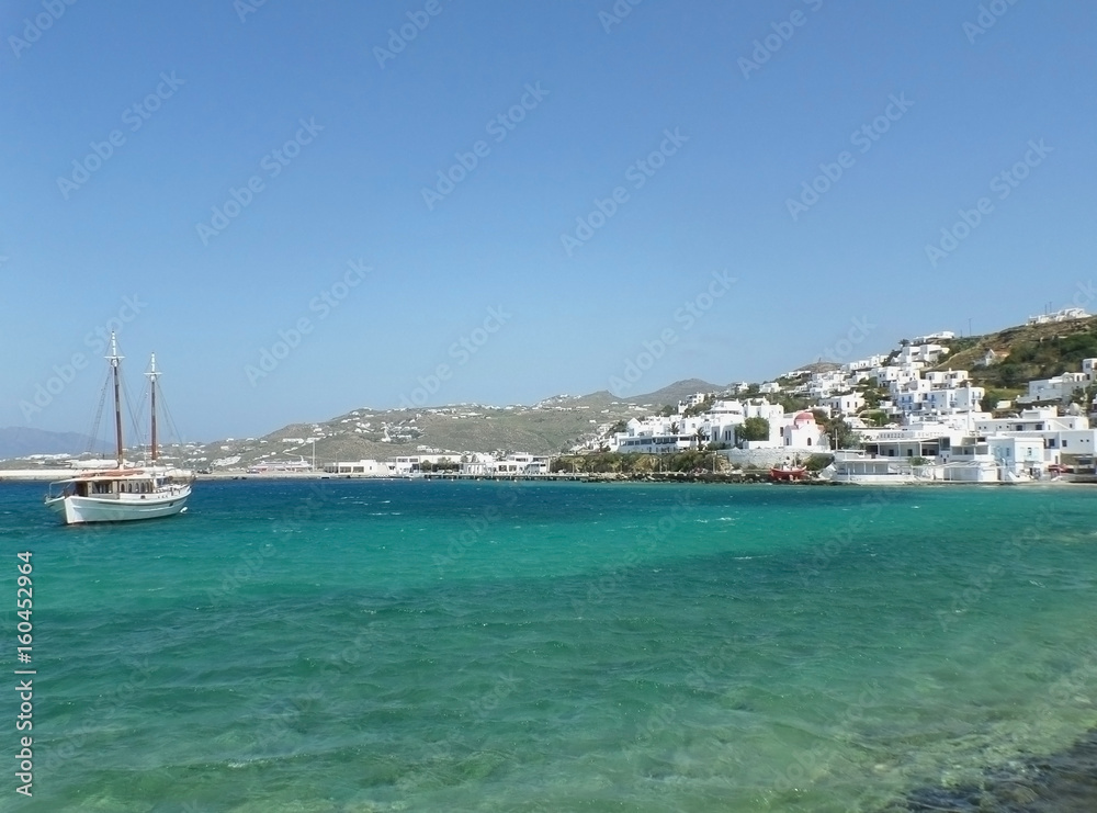 White fishing boat and little town between blue sky and blue sea, Mykonos Island, Greece